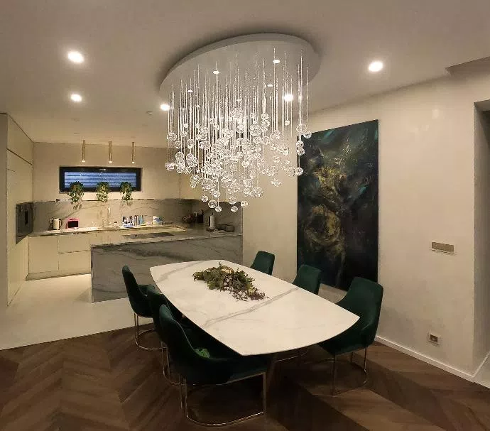 Eliptical AQUILA chandelier made of fiber optics and glass components above dining table