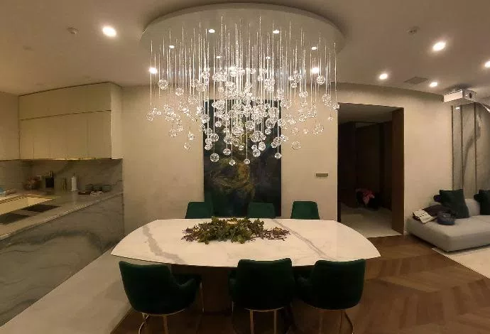 Eliptical shape chandelier in modern interior above marble table in dining room