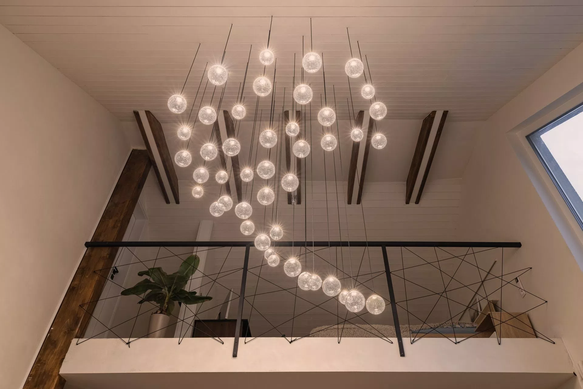 2-storey massive baseless chandelier with soda glass ball components and LED technology viewed from bellow in livingroom.